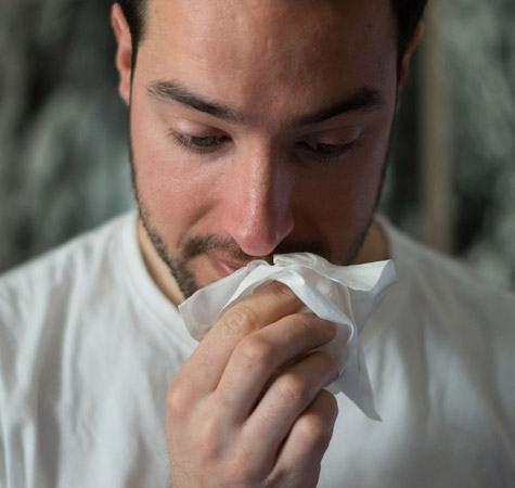 Man wiping nose with tissue